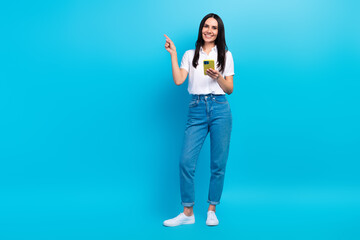 Full length photo of dreamy pretty lady wear white shirt typing modern device pointing empty space isolated blue color background