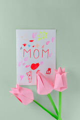 Tulips made of colored paper with a postcard with the inscription "Mom" on a green background, handmade. Mother's day, women's day concept.