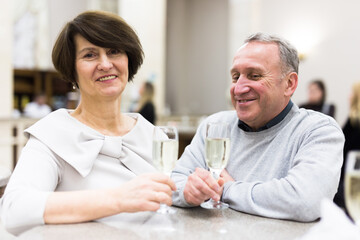 Mature man and woman drinking champagne in theater lobby