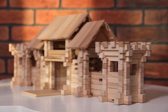 Wooden gate on white table near brick wall, closeup. Children's toy