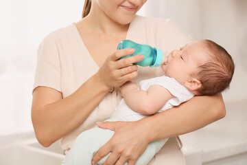 Obraz na płótnie Canvas Mother feeding her cute child with infant formula indoors