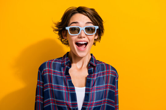 Fototapeta Photo of astonished woman dressed plaid shirt staring at unbelievable visual illusion in 3d glasses isolated on yellow color background