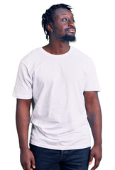 Obraz premium Young african american man with braids wearing casual white tshirt smiling looking to the side and staring away thinking.