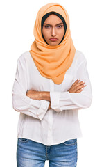 Young brunette woman wearing traditional islamic hijab scarf skeptic and nervous, disapproving...
