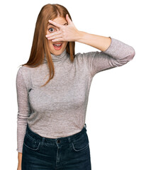 Young irish woman wearing casual clothes peeking in shock covering face and eyes with hand, looking through fingers with embarrassed expression.