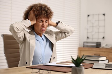 Woman suffering from headache at workplace in office