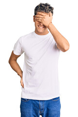 Young handsome man wearing casual white tshirt smiling and laughing with hand on face covering eyes for surprise. blind concept.