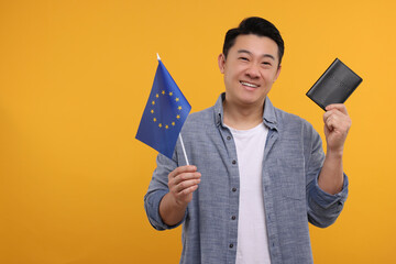Immigration. Happy man with passport and flag of European Union on orange background, space for text