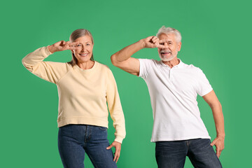 Senior couple dancing together on green background