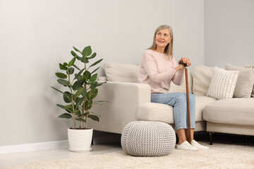 Mature woman with walking cane on sofa at home
