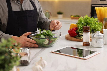 Man cooking salad at white marble countertop in kitchen, closeup