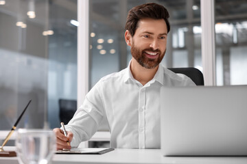 Portrait of smiling man working with laptop in office, space for text. Lawyer, businessman, accountant or manager