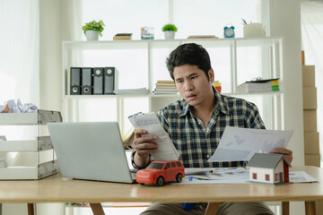 Young Asian man calculates car payments Home installments in financial planning and income Asset...
