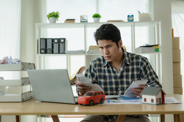 Young Asian man calculates car payments Home installments in financial planning and income Asset...