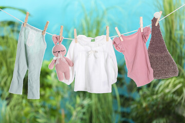 Baby clothes and bunny toy drying on laundry line outdoors