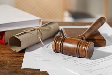 Notary contract. Gavel, documents and books on wooden table, closeup