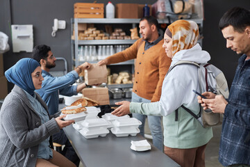 Side view portrait of group of Middle Eastern people standing in line at soup kitchen with...