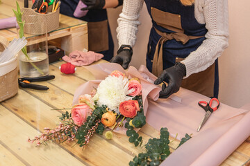 Female florist preparing boquet of roses in the shop. Close up girl creating the compose of flowers