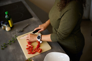 Close-up young woman chopping vegetables, cooking healthy raw vegan salad for dinner in the...