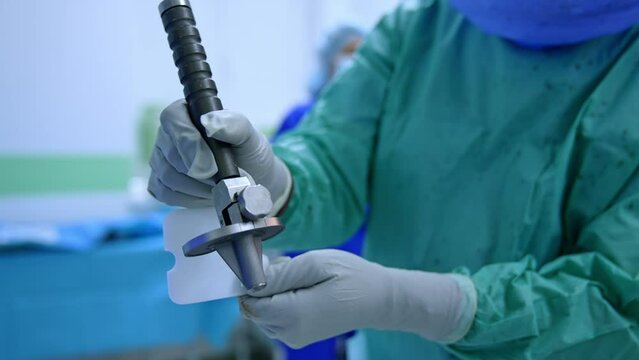 Unrecognized doctor in latex gloves holding an orthopedic device. Preparation for trauma surgery.
