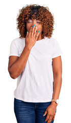 Young african american woman wearing casual white tshirt bored yawning tired covering mouth with...