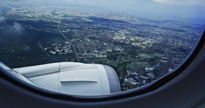 Airplane flight. Wing of an airplane flying above the city skyline. View from the window of the plane. The plane is descending over the city. Traveling by air. 4K real time video.