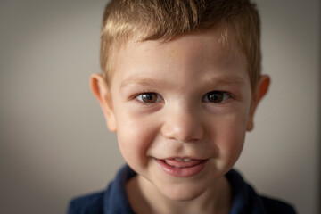 Retrato de niño pequeño rubio sonriendo mirando a la cámara 