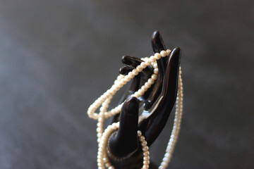 Jewlery stand shaped like a hand with pearl necklace. Selective focus.