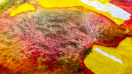 Close-up texture of watercolor stroke on textured paper. Macro watercolour stain colors red yellow with green granulation. Film grain pixel texture. Soft focus. Blur. Live camera. Creation background.