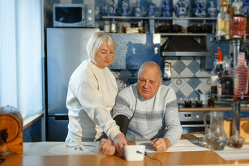 Fototapeta na wymiar An elderly woman measures her husband's blood pressure