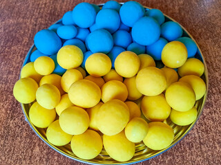 Blue and yellow chocolate dragee. Chocolate dragee on a wood background close up