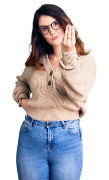 Beautiful young brunette woman wearing casual clothes and glasses doing italian gesture with hand and fingers confident expression