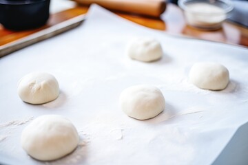 unbaked naan dough balls lined up on a floured surface