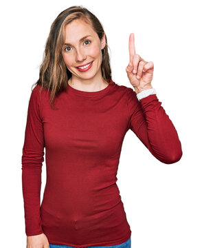 Young blonde woman wearing casual clothes pointing finger up with successful idea. exited and happy. number one.