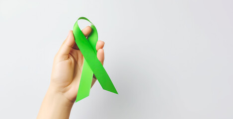 hand hold green ribbon for awareness , donoation, Liver cancer, a mental health , lymphoma,