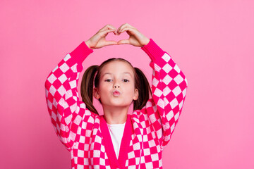 Photo of lovely schoolgirl with tails dressed knit cardigan arms showing heart over head send air kiss isolated on pink color background