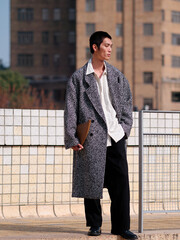 Portrait of handsome Chinese young man with black short hair wearing woolen coat posing with modern city building background in sunny winter day, male fashion, cool Asian young man.