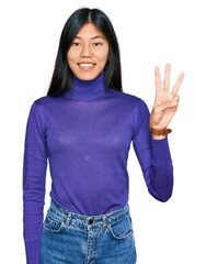 Beautiful young asian woman wearing casual clothes showing and pointing up with fingers number three while smiling confident and happy.
