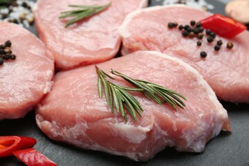 Pieces of raw pork meat, chili pepper and spices on board, closeup