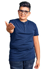 Fototapeta premium Little boy kid wearing casual clothes and glasses smiling friendly offering handshake as greeting and welcoming. successful business.