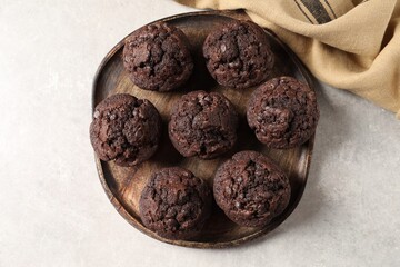 Board with delicious chocolate muffins on light table, top view