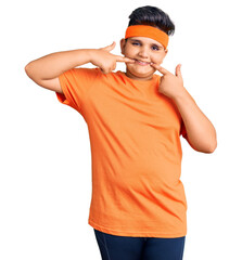 Little boy kid wearing sportswear smiling cheerful showing and pointing with fingers teeth and mouth. dental health concept.
