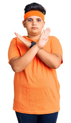 Little boy kid wearing sportswear rejection expression crossing arms doing negative sign, angry face