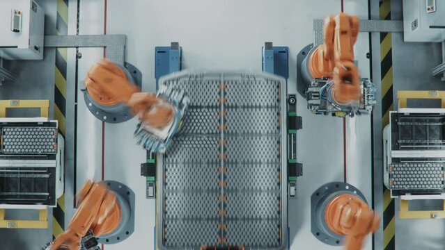 Top View of Automated Production Line with Robotic Arms. EV Battery Pack for Automotive Industry Assembly. Electric Car Smart Factory. Manufacturing Line Equipped with Robot Arms