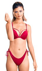 Fototapeta premium Young beautiful woman wearing bikini doing italian gesture with hand and fingers confident expression