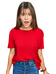 Fototapeta premium Teenager caucasian girl wearing casual red t shirt afraid and shocked with surprise and amazed expression, fear and excited face.