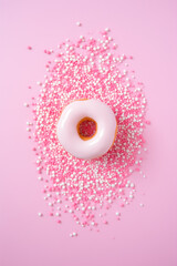 Flat lay of a donut with sprinkles on a pink background.Pastel pink color.Minimal concept.
