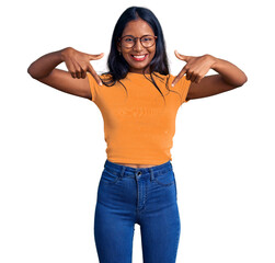 Young indian girl wearing casual clothes and glasses looking confident with smile on face, pointing oneself with fingers proud and happy.