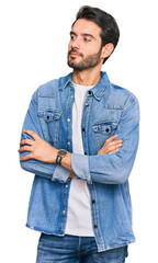 Young hispanic man wearing casual clothes looking to the side with arms crossed convinced and confident