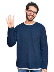 Fototapeta premium Young hispanic man wearing casual clothes and glasses showing and pointing up with fingers number four while smiling confident and happy.